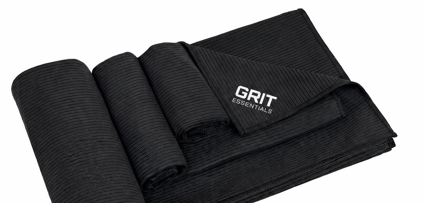 Toalla GRIT de microfibra negra, enrollada y desplegada